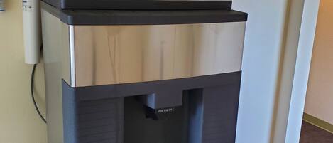 A stainless steel water dispenser with a black top and a push button for dispensing water.