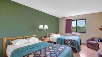 A hotel room with two beds, a window with a view, a chair, and a nightstand with a lamp.
