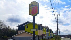 Un motel à plusieurs étages, reconnaissable à son grand panneau « Super 8 », qui présente un design moderne avec une combinaison de couleurs jaune et bleu.