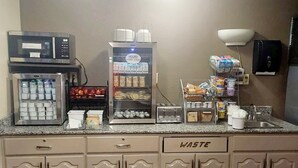 Une petite cuisine équipée d’un four à micro-ondes, d’un réfrigérateur et de différents récipients pour conserver les aliments.