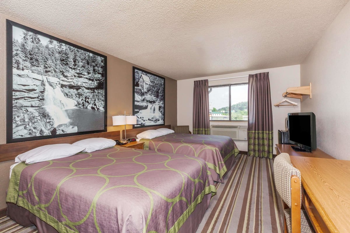 Een hotelkamer met twee bedden, een televisie, een bureau en grote foto's van watervallen in lijsten.