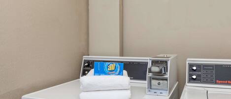 A front-loading washing machine with a blue detergent box and a white towel on top.