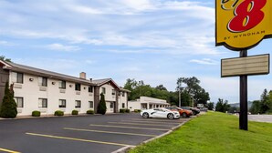 A hotel with a parking lot, a Super 8 sign, and a building with a flat roof and multiple windows. - Super 8 by Wyndham Elkins (Elkins)