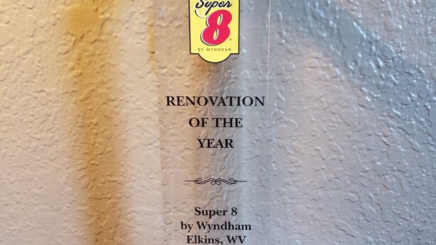 A clear acrylic award plaque with the text "Super 8 by Wyndham Elkins, WV 2018-2019" against a textured wall background. - Super 8 by Wyndham Elkins (Elkins)