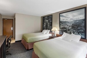 Habitación de hotel con dos camas, un escritorio y una silla.