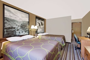Habitación de hotel con dos camas, un escritorio, una silla y dos lámparas fijadas a la pared.