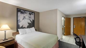 Una habitación de hotel con cama, mesita de noche, lámpara y un cuadro abstracto grande en la pared.