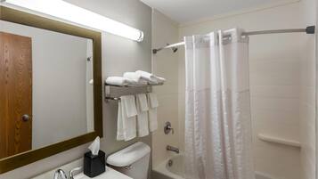 A bathroom with a wooden door, a mirror, a sink with chrome fixtures, a toilet, a bathtub, and a shower curtain.