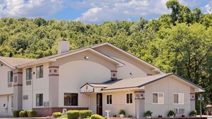 A two-story building with a beige facade, a prominent 'Lobby' sign, and a landscaped front yard with shrubs and a small white planter. - Super 8 by Wyndham Elkins (Elkins)