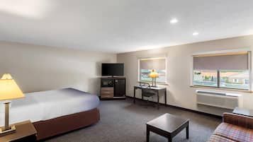 A hotel room with a bed, desk, chair, and a television.