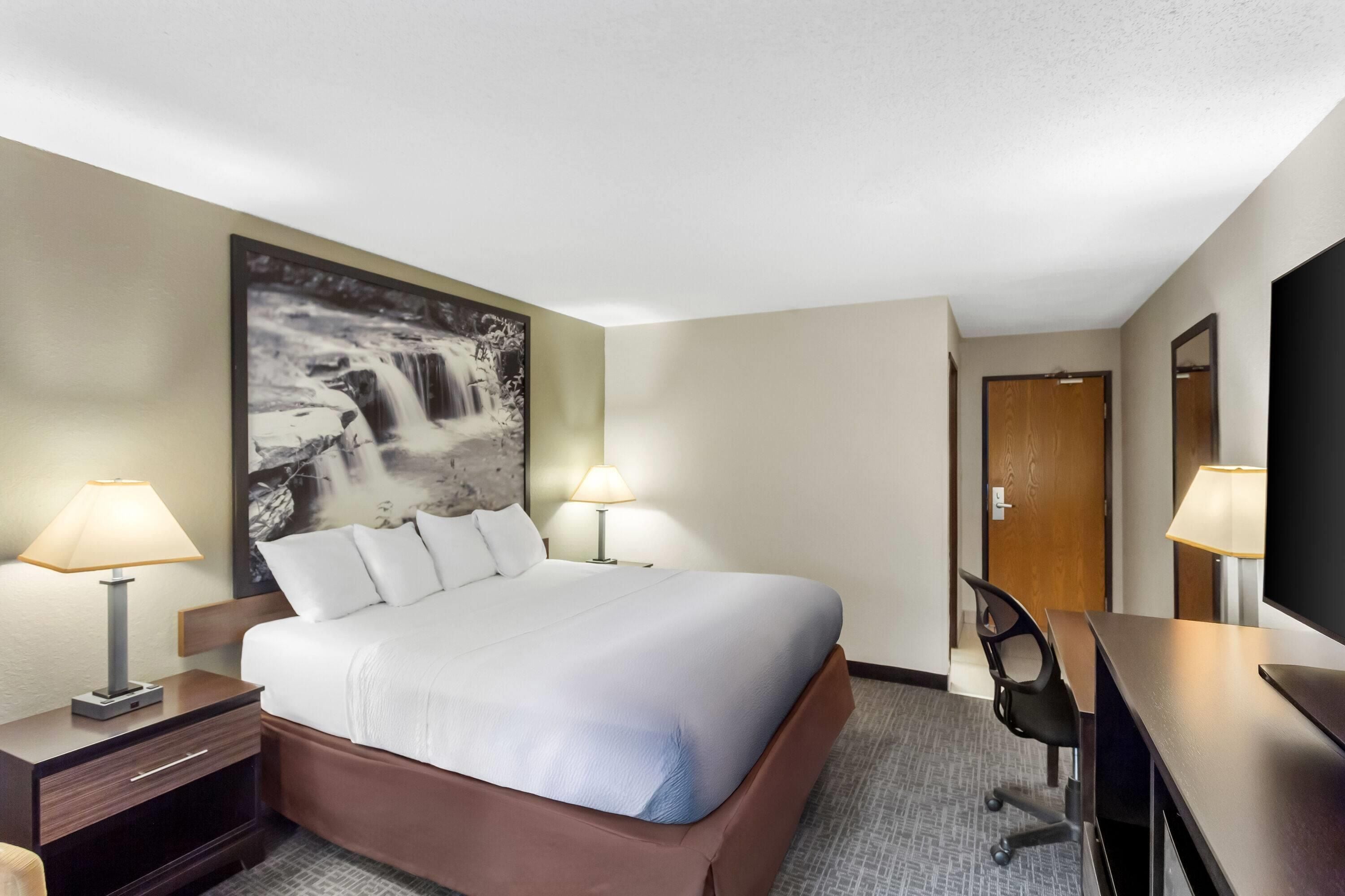 Une chambre d’hôtel avec un grand lit, deux lampes de chevet, un bureau et une chaise.