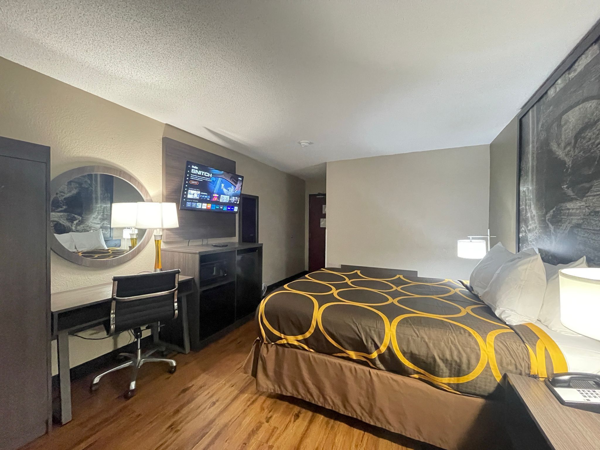 Une chambre d’hôtel comprenant un lit, un bureau avec une chaise, une télévision et un grand miroir.