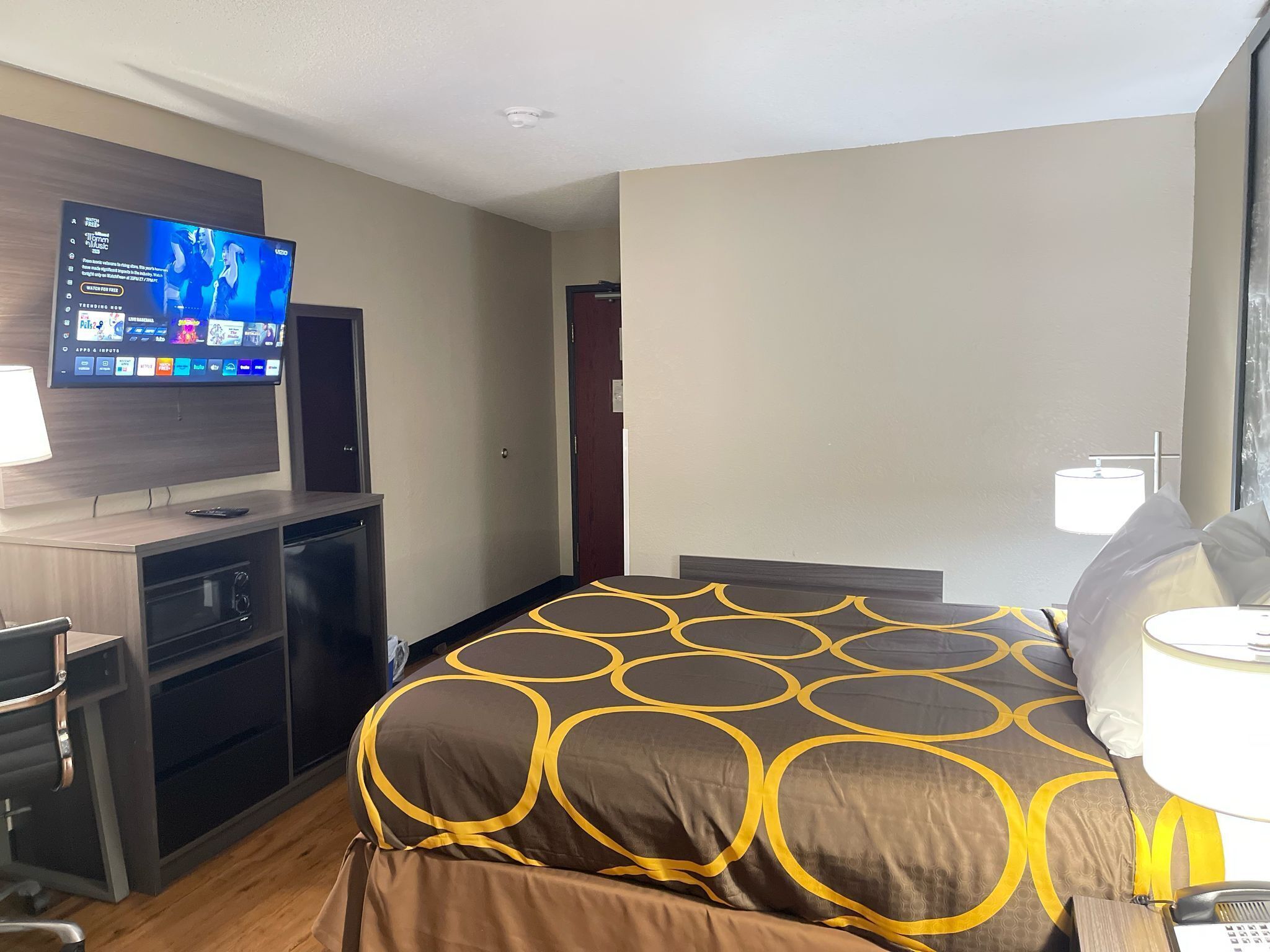 Habitación de hotel con cama, escritorio con televisor, lámpara y teléfono.