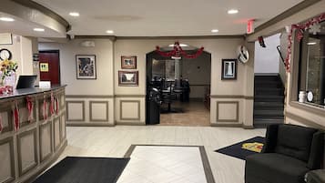 A hotel lobby with a reception desk, framed pictures on the walls, a staircase, and a Christmas decoration.