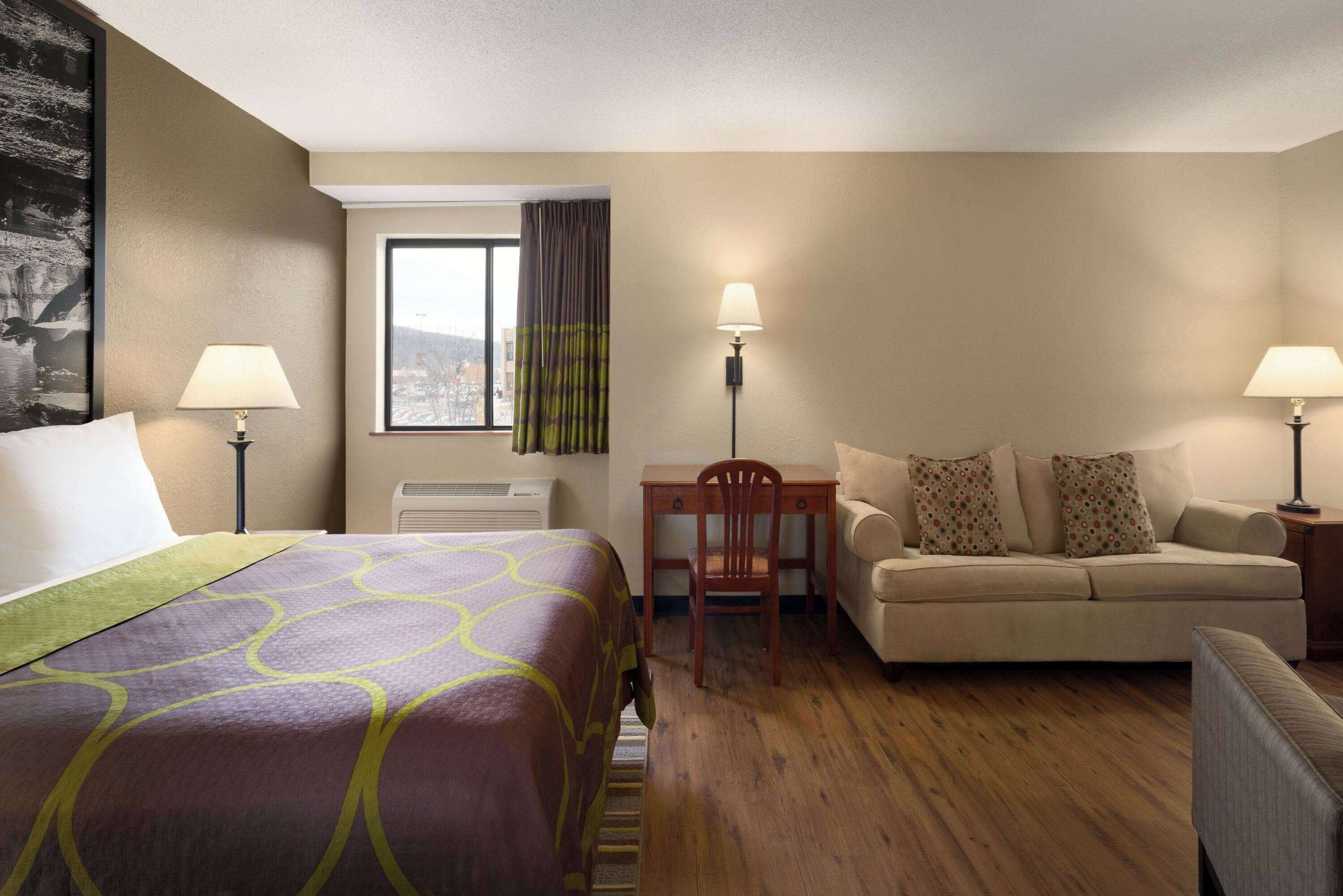 A hotel room with a bed, a sofa, a desk, and a chair.