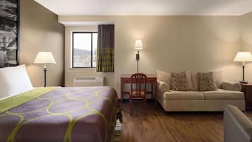 A hotel room with a bed, a sofa, a desk, and a chair.
