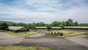 A building with multiple rooms, a parking lot, and a grassy area with trees. - Econo Lodge Hornell (Hornell)
