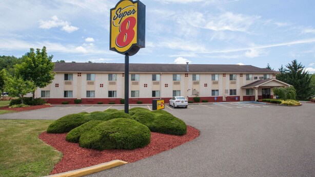 Um motel Super 8 com estacionamento, um edifício de fachada bege e céu claro.