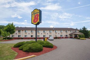 Un motel Super 8 con estacionamiento, un edificio de fachada color beige y un cielo despejado.