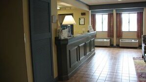 A hotel reception area with a reception desk, air conditioning units, and a window with curtains. - Quality Inn Cortland - University Area (Cortland)