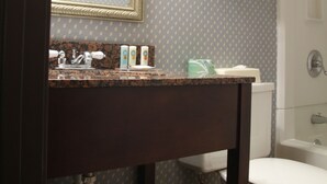 A bathroom with a sink, mirror, and toilet. - Quality Inn Cortland - University Area (Cortland)