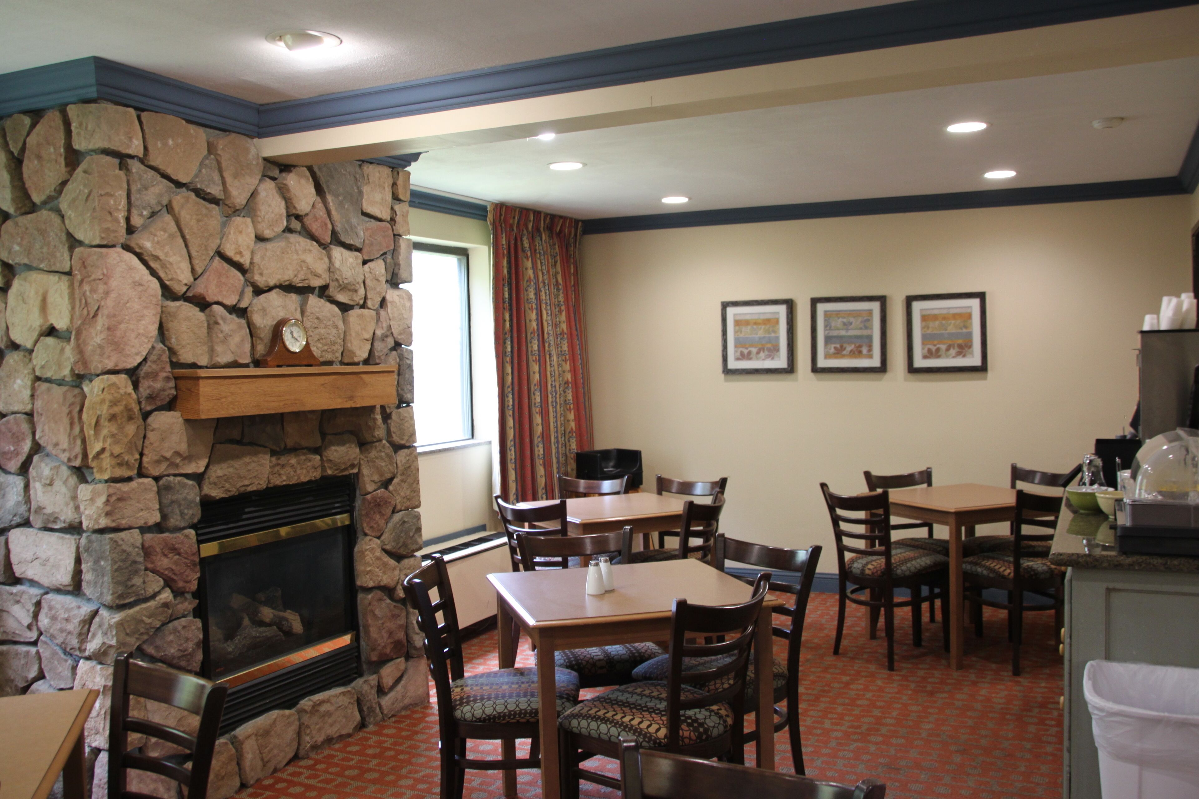 A dining area with stone walls, a fireplace, and multiple tables and chairs.
