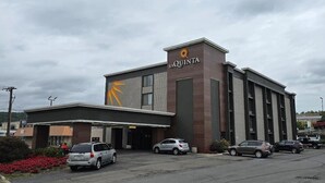 Un hotel con un logotipo llamativo, un acceso cubierto y varios espacios de estacionamiento.
