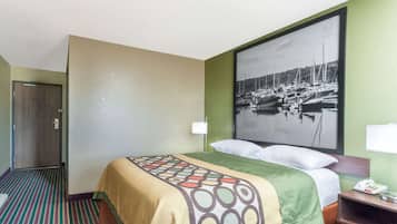 Quarto de hotel com cama, mesa de cabeceira, telefone e um quadro na parede retratando um porto.