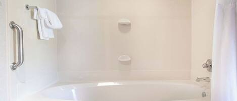 A modern bathroom with a freestanding bathtub, a handheld showerhead, and a towel rack.