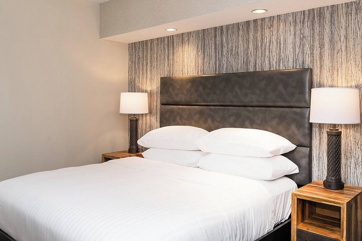 A hotel room with a large bed, two bedside tables with lamps, and a textured wall behind the bed.