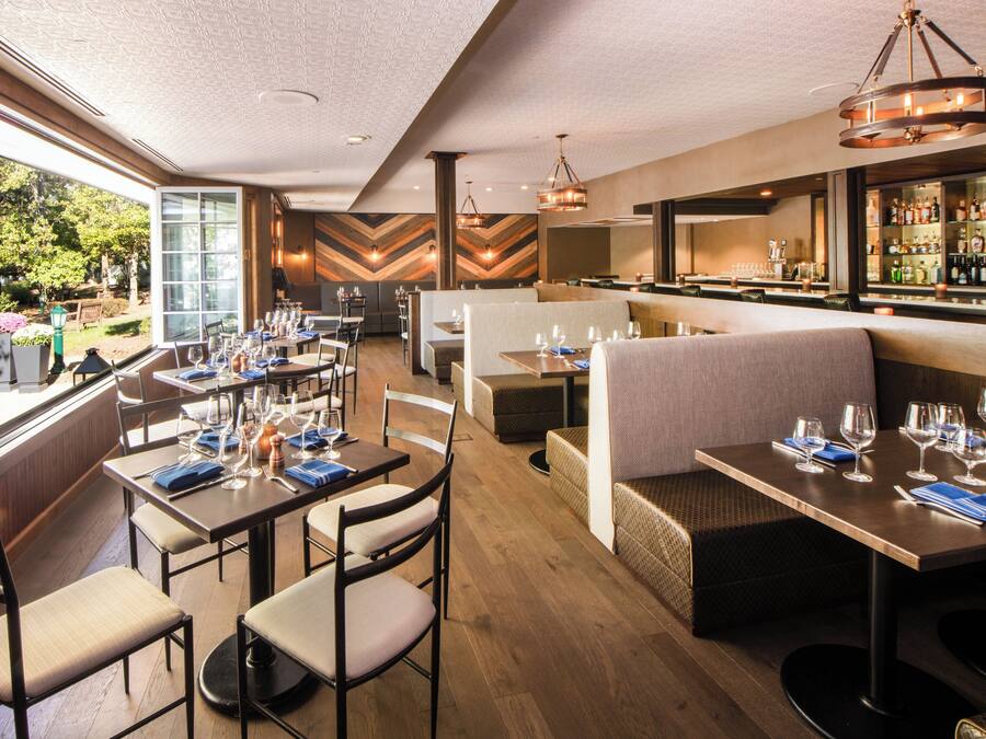 A restaurant with multiple dining areas, including booths and tables, and a bar with a variety of bottles.