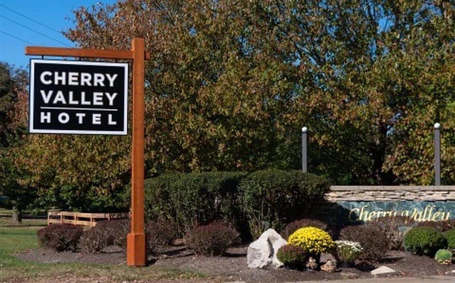 Un letrero para el Hotel Cherry Valley con un poste de madera y fondo negro.