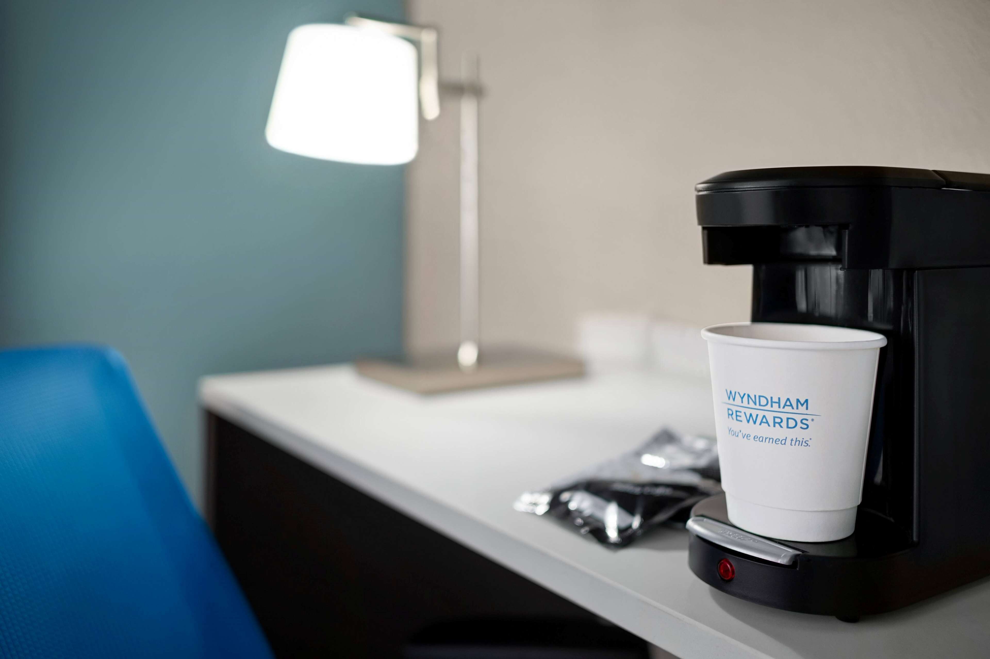 A coffee maker with a cup labeled "Wyndham Rewards" on a hotel counter.