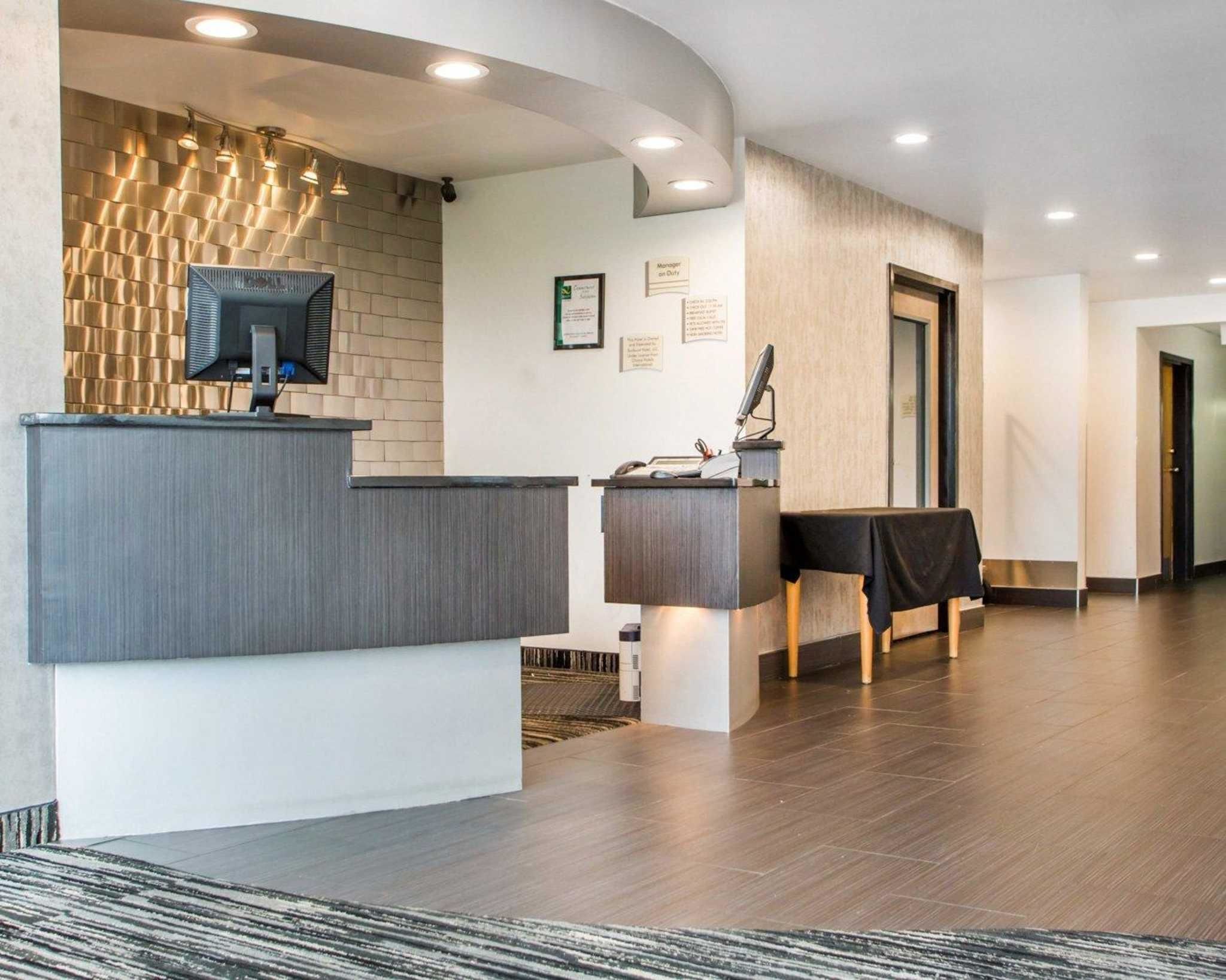 A modern reception area with a curved desk, a flat-screen TV, and a small table with a telephone.