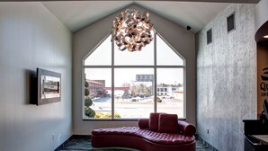 A modern hotel lobby with a large window, a unique red seating area, and a contemporary chandelier. - Quality Inn & Suites North/Polaris (Columbus)