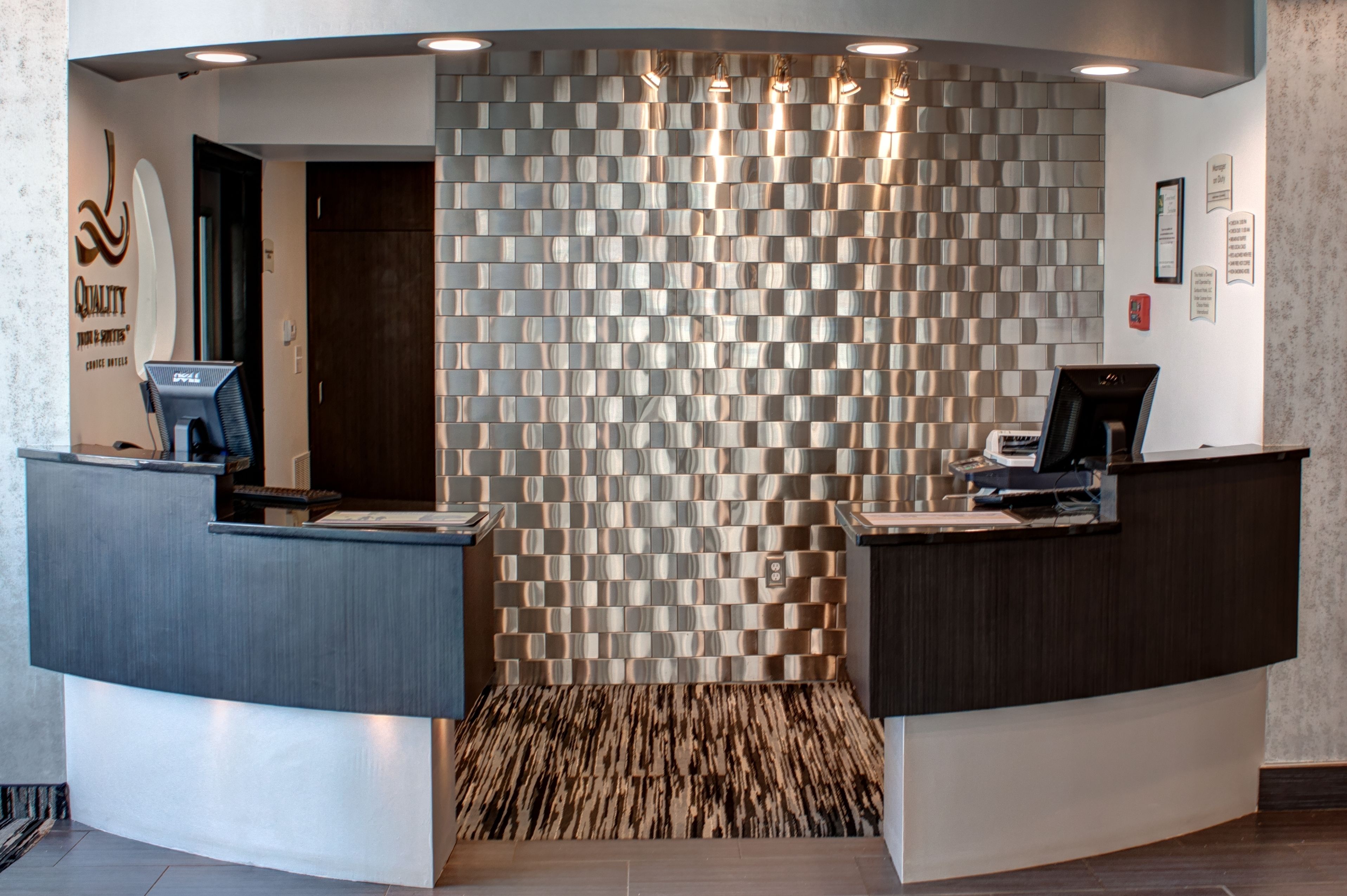 A reception area with a modern design, featuring a patterned wall and two reception desks.