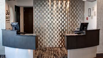 A reception area with a modern design, featuring a patterned wall and two reception desks.