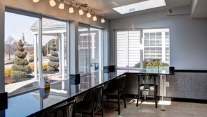 A modern kitchen with a glass countertop, bar stools, and large windows offering views of the outside. - Quality Inn & Suites North/Polaris (Columbus)