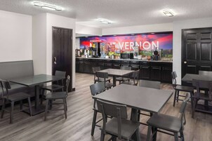 A modern kitchen with a large island, dark wooden cabinets, and a colorful mural on the wall.