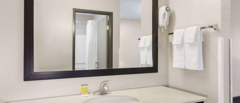 A bathroom with a large mirror, a sink, a towel rack, and a hairdryer.