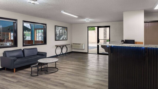 Un interior moderno con un sofá, una mesa redonda y una zona de cocina con mostrador y fregadero.