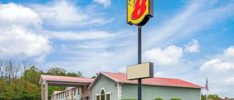 Ein Super 8 Hotel mit rotem Dach, überdachtem Parkplatz und einer Fahnenstange mit der US-amerikanischen Flagge.