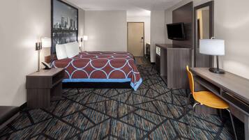 Habitación de hotel con cama, escritorio, silla, televisión y un cuadro de la ciudad en la pared.