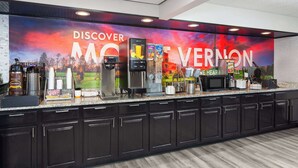 Una cocina con un gran mural, cafeteras y un microondas.