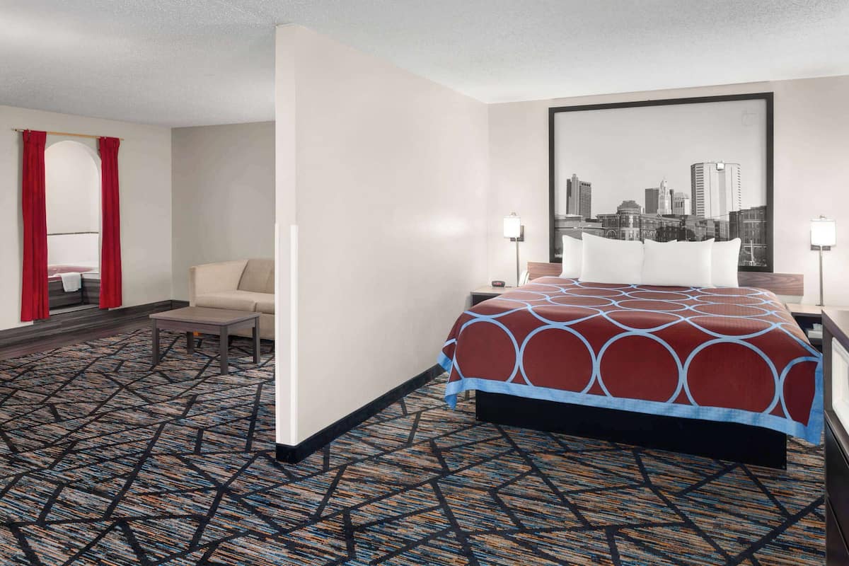 Hotelkamer met een bed, een bureau, een stoel, een stadsgezicht aan de wand en een kamerbreed tapijt met dessin.