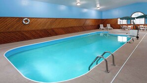 Una piscina interior con paneles de madera, un flotador salvavidas y sillones de descanso.