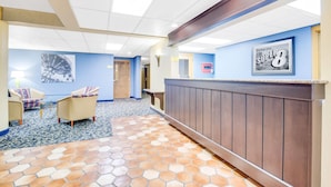 A hotel lobby with a reception desk, seating area, and a tiled floor. - Super 8 by Wyndham Port Clinton (Port Clinton)