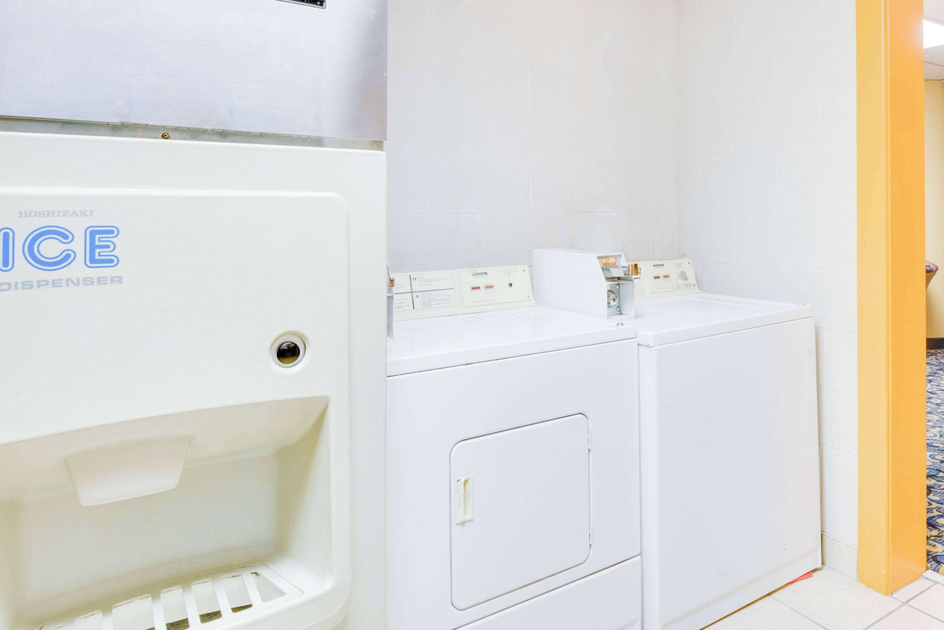 Un espace buanderie avec un distributeur de glaçons blanc et deux machines à laver blanches.