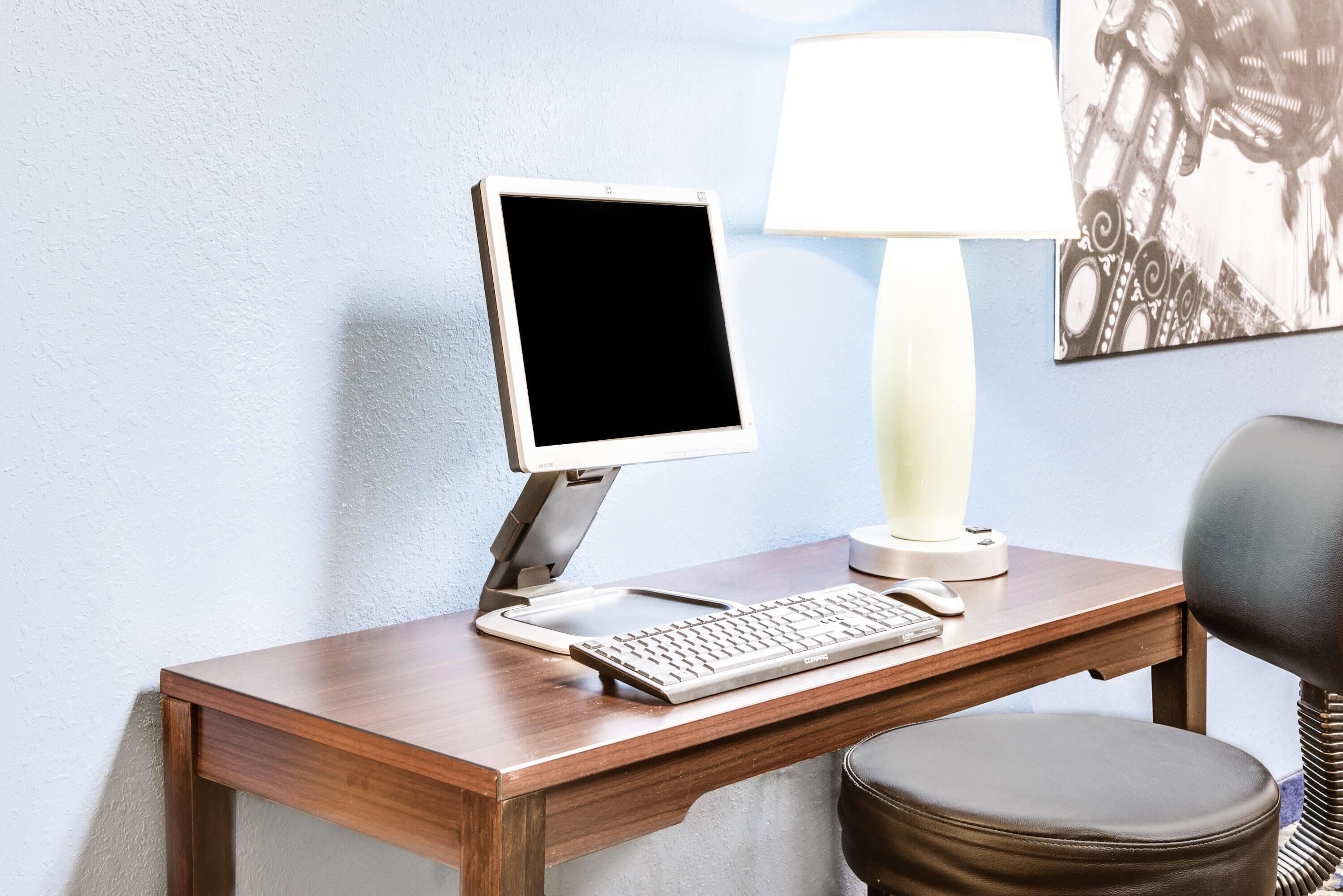Un escritorio de madera con una computadora de escritorio, una lámpara y una silla.