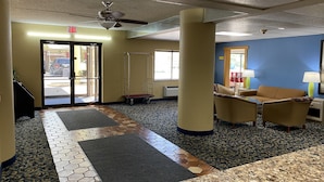 A hotel lobby with a tiled floor, a reception desk, a seating area with chairs, and a ceiling fan. - Super 8 by Wyndham Port Clinton (Port Clinton)